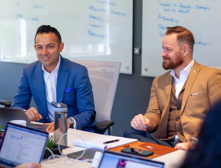 Tekion employees discussing business strategy at their desks in a collaborative work environment