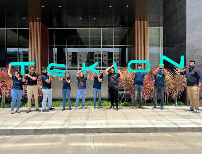 Tekion employees showcasing company spirit by holding letter signs spelling Tekion
