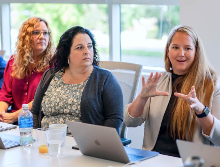 Three Tekion women professionals discussing Tekion’s cloud-native automotive platform