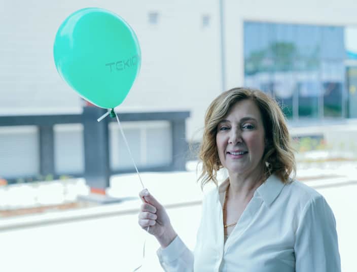 Tekion team member celebrating company culture with a branded Tekion balloon