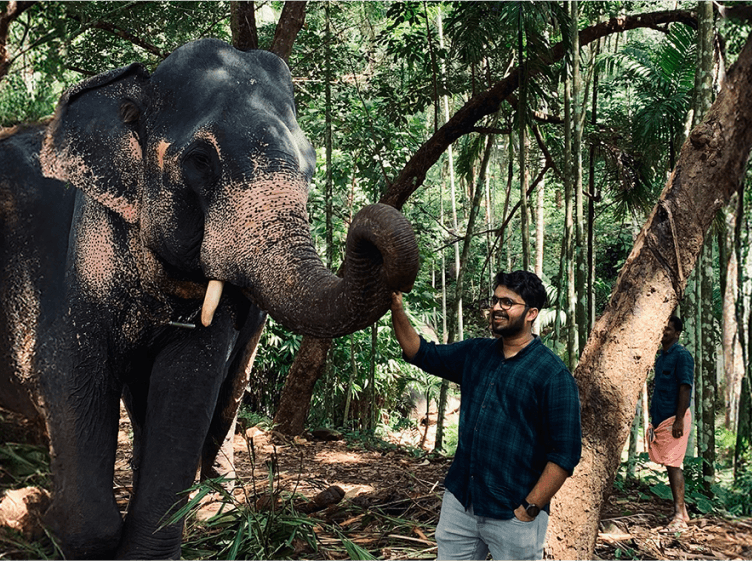 Tekion employee standing near an elephant, embodying the diverse and adventurous culture of the company
