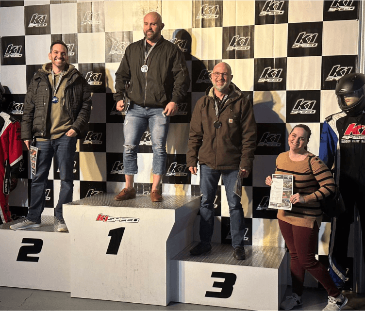Tekion employees standing on a podium, celebrating success and teamwork in cloud-native automotive technology